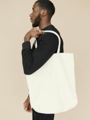 Profile of a young man holding a white tote bag, showcasing eco-fashion.