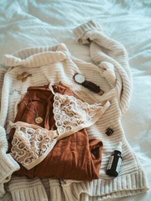 Stylish morning setup with cozy clothes and accessories on a bed.